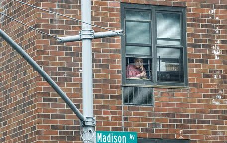 epa08341705 A woman leans out of her window to smoke in New York, New York, USA, on 03 April 2020. New York City is still considered the epicenter of the coronavirus outbreak in the United States and most people are still being asked to stay at home to stop the spread of the conornavirus.  EPA/JUSTIN LANE