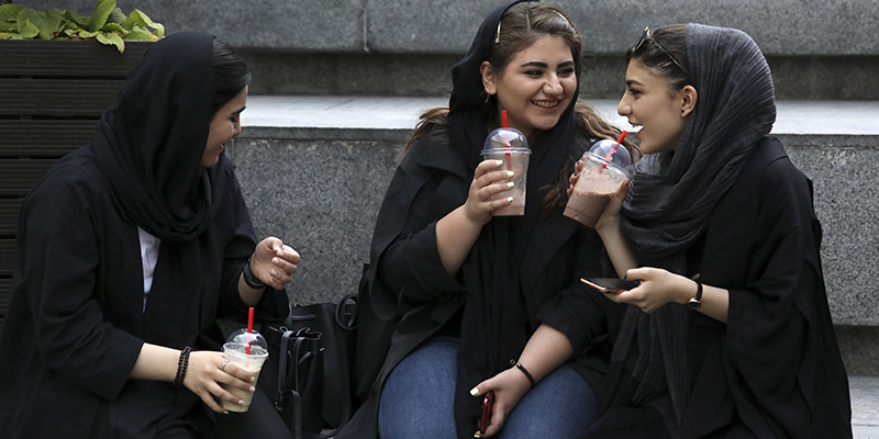 In this Tuesday, July 2, 2019 photo, youngsters spend an afternoon while siting on steps outside a shopping mall in northern Tehran, Iran.  A few daring women in Iran's capital have been taking off their mandatory headscarves, or hijabs, in public, risking arrest and drawing the ire of hard-liners. Many others stop short of outright defiance and opt for loosely draped scarves that show as much hair as they cover. More women are pushing back against the dress code imposed after the 1979 Islamic Revolution, and activists say rebelling against the hijab is the most visible form of anti-government protest in Iran today.  (AP Photo/Vahid Salemi)